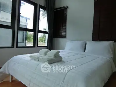 Bright and cozy bedroom with large windows and fresh linens, perfect for relaxation.