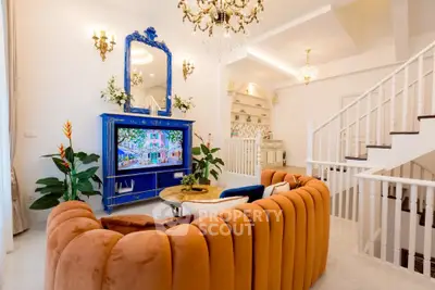 Luxurious living room with elegant chandelier and plush orange sofa, featuring a stylish blue entertainment center.