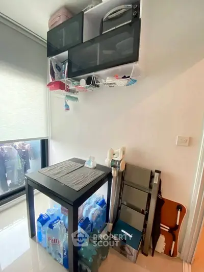 Compact storage area with table, ladder, and household supplies in modern apartment.