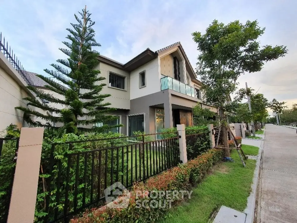 Modern two-story house with lush garden and spacious balcony in a serene neighborhood.