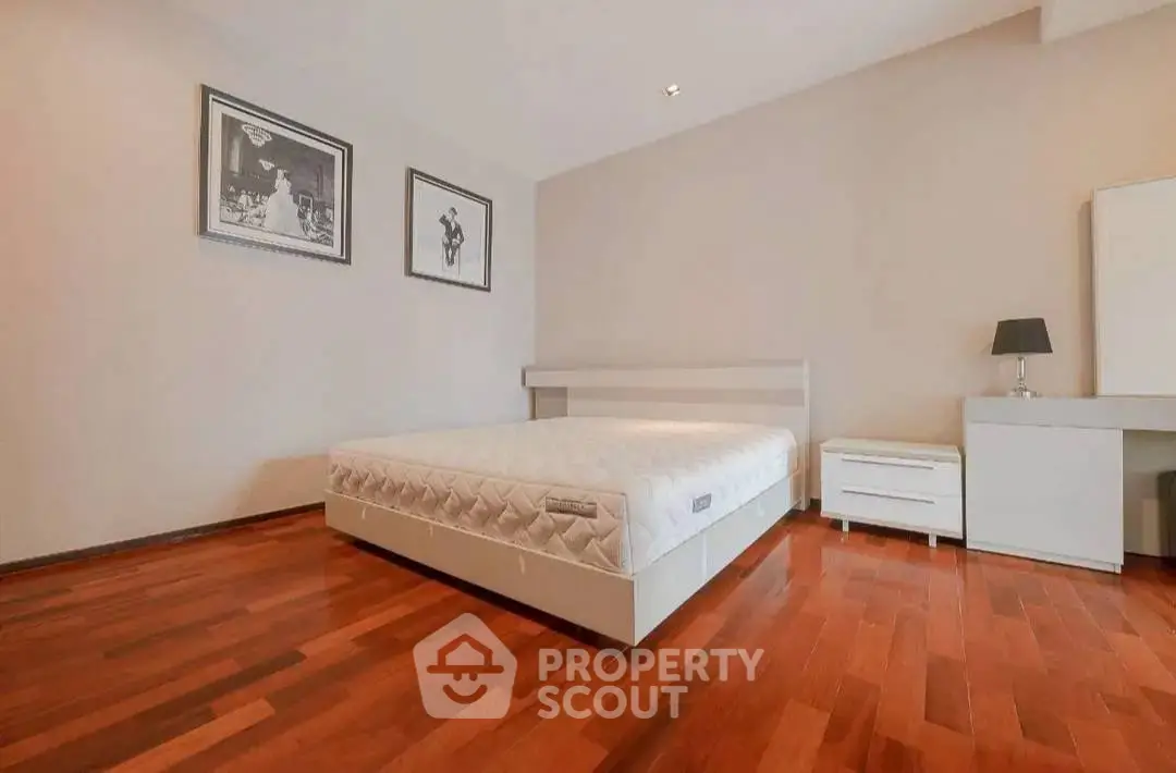 Spacious bedroom with wooden flooring and modern decor in a stylish apartment.