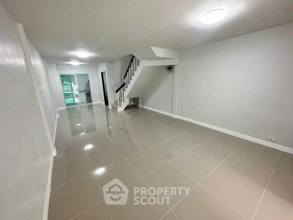 Spacious modern living room with sleek tile flooring and staircase, perfect for contemporary living.