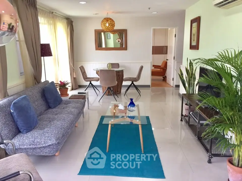 Spacious living room with modern decor, large windows, and stylish furniture in a bright apartment.