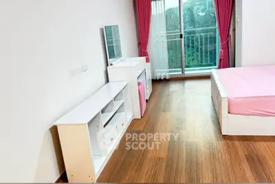 Spacious bedroom with balcony and pink accents in modern apartment