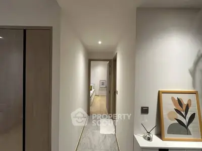 Modern hallway leading to a cozy bedroom with stylish decor and wooden flooring.