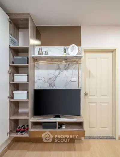Modern living room with stylish shelving and flat-screen TV, featuring elegant marble accents and wooden flooring.