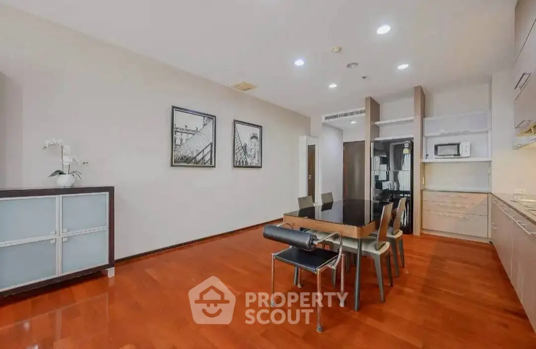Spacious dining area with modern kitchen and elegant wooden flooring.