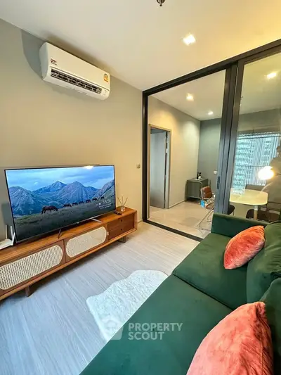 Modern living room with green sofa, large TV, and stylish decor in a contemporary apartment.
