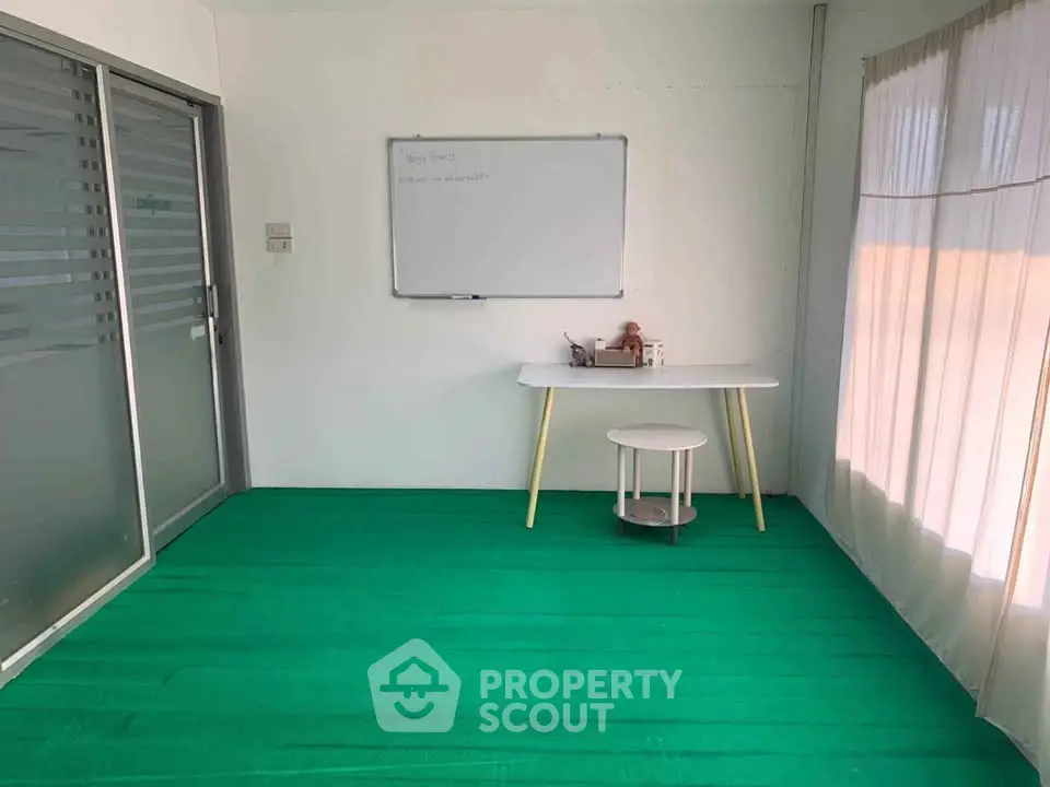 Bright study room with green carpet and natural light, perfect for productivity.