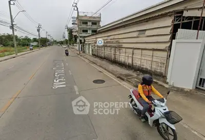 Street view of industrial building with motorcyclist passing by