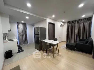 Modern open-plan living room with kitchen and dining area, featuring sleek furniture and contemporary design.