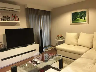 Modern living room with sleek furniture and large TV, featuring elegant decor and natural light.
