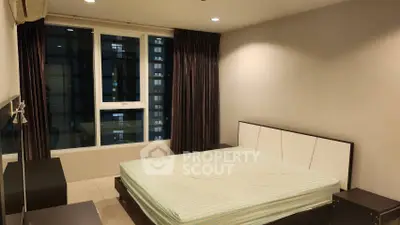 Spacious bedroom with large window and modern furnishings in a high-rise apartment.