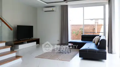 Modern living room with sleek furniture and large window offering natural light