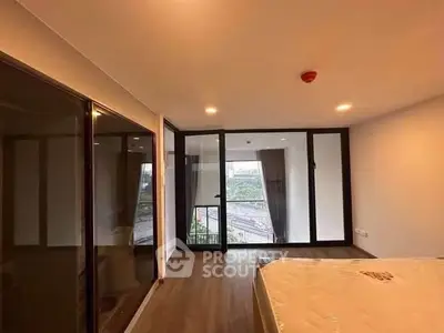 Spacious bedroom with large windows and balcony access, offering natural light and modern design.