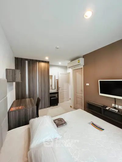 Modern bedroom with sleek furniture and wall-mounted TV, featuring a cozy workspace and ample storage.