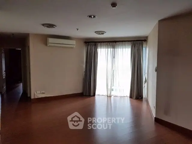 Spacious living room with wooden flooring and large window for natural light.
