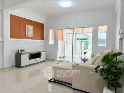 Modern living room with sleek furniture and large glass doors leading to a bright outdoor area.