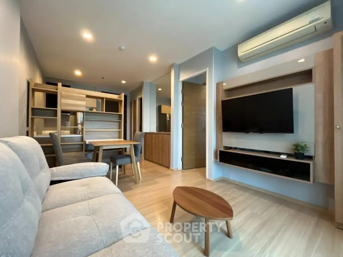 Modern living room with stylish furniture and wall-mounted TV in a cozy apartment.
