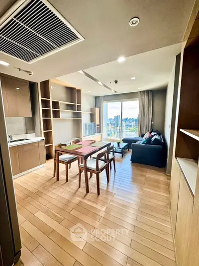 Modern open-layout living room with kitchen and city view, featuring wooden flooring and stylish furniture.