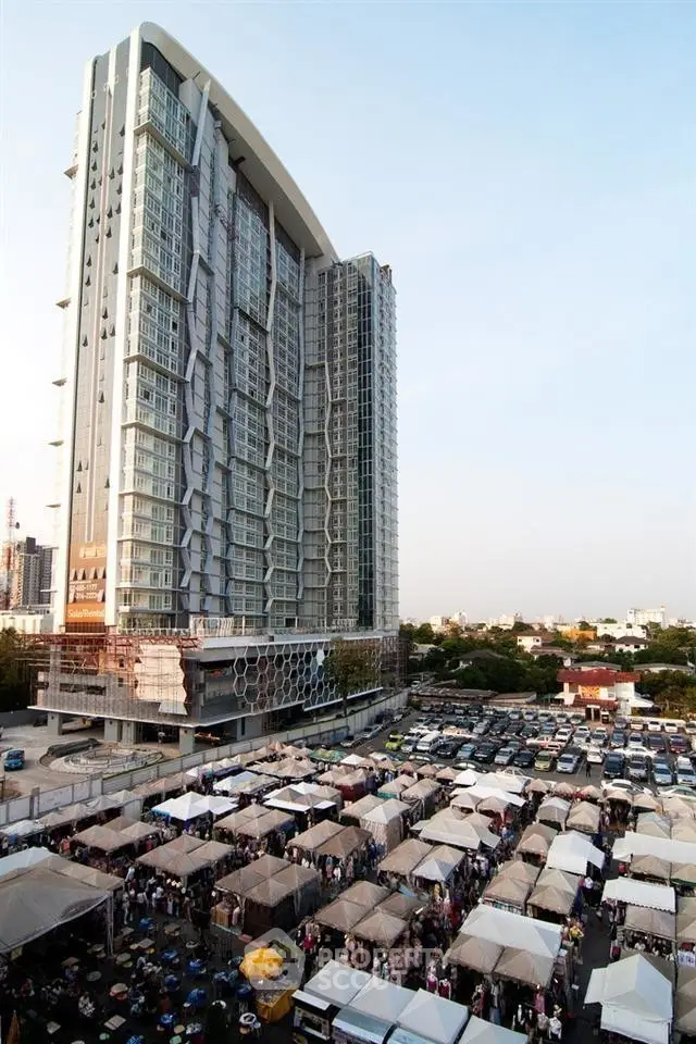 Modern high-rise building with bustling market below, showcasing urban living.