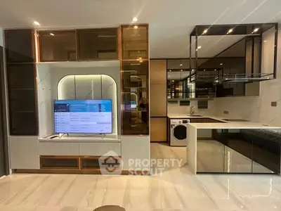 Modern living room with sleek kitchen, built-in TV unit, and washing machine, showcasing contemporary design.