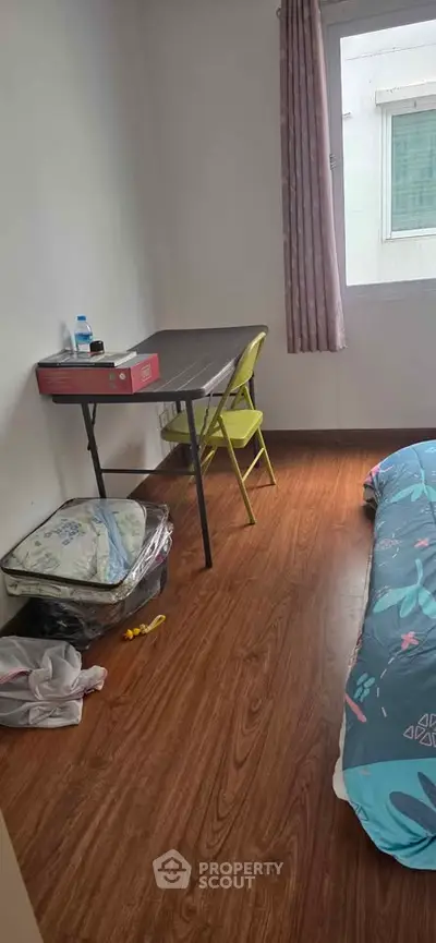 Cozy bedroom with wooden flooring and simple furnishings, perfect for minimalist living.