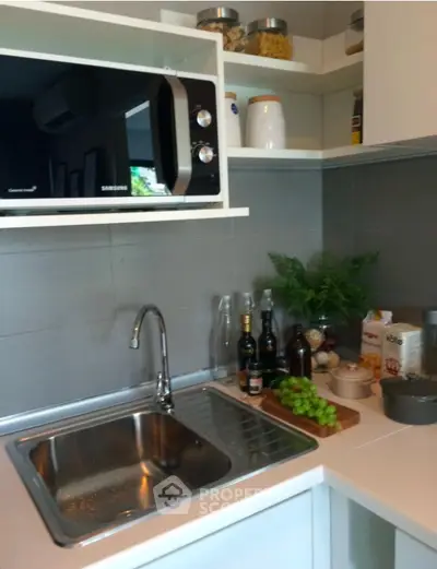 Modern kitchen with sleek design, featuring a microwave, sink, and stylish shelving.