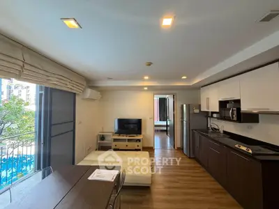 Modern open-layout living room with kitchen, featuring sleek appliances and a view of the pool.