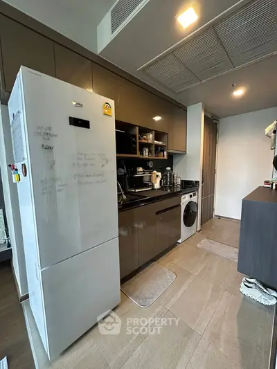 Modern kitchen with sleek cabinetry and appliances, including a washing machine and refrigerator.