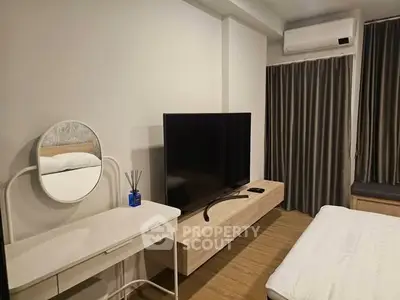 Modern bedroom with sleek TV setup and stylish vanity in a cozy apartment.