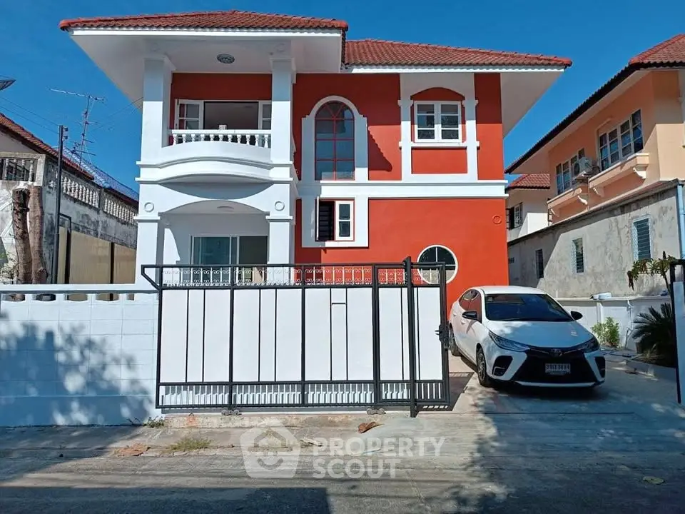 Charming two-story red house with gated driveway and car parked in front, perfect suburban living.