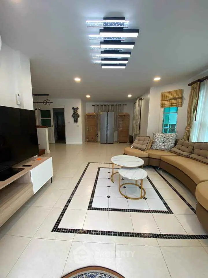 Spacious living room with modern decor and stylish lighting, featuring a large sectional sofa and sleek TV setup.