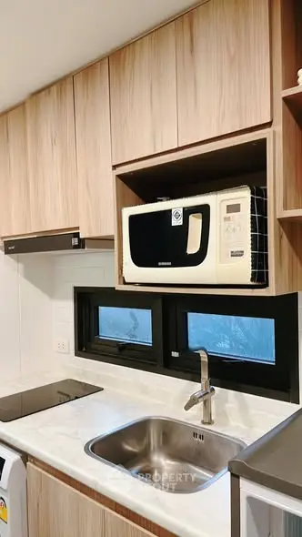 Modern kitchen with sleek cabinetry and built-in microwave above sink