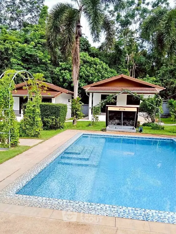 Stunning tropical property with lush greenery and inviting swimming pool, perfect for relaxation and leisure.