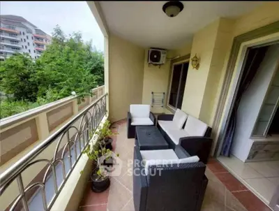 Spacious balcony with outdoor seating and lush greenery view in modern apartment.
