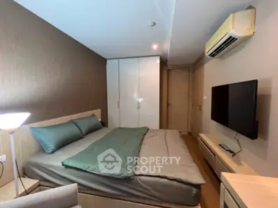 Modern bedroom with sleek design, featuring a comfortable bed, wall-mounted TV, and air conditioning.