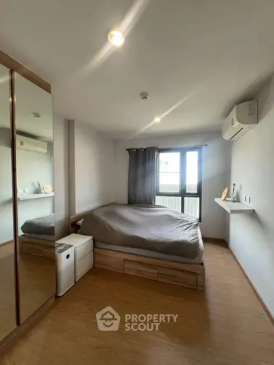 Modern bedroom with sleek design, featuring a large window and air conditioning unit.