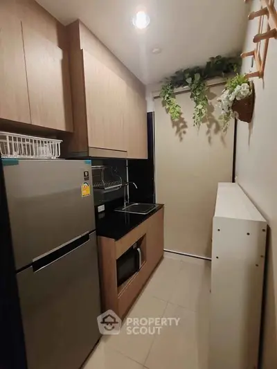 Modern compact kitchen with sleek cabinetry and stainless steel appliances in a cozy apartment.