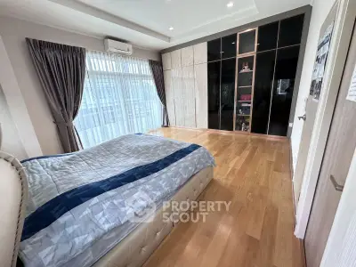 Spacious bedroom with elegant wooden flooring and large windows for natural light.