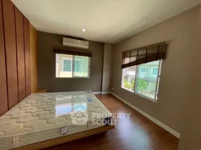 Spacious bedroom with large windows and wooden flooring in a modern home