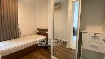 Cozy bedroom with wooden flooring and mirrored wardrobe in modern apartment.