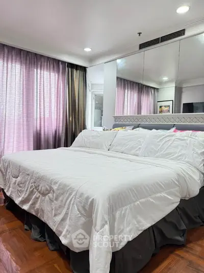 Spacious bedroom with elegant decor and large windows for natural light.