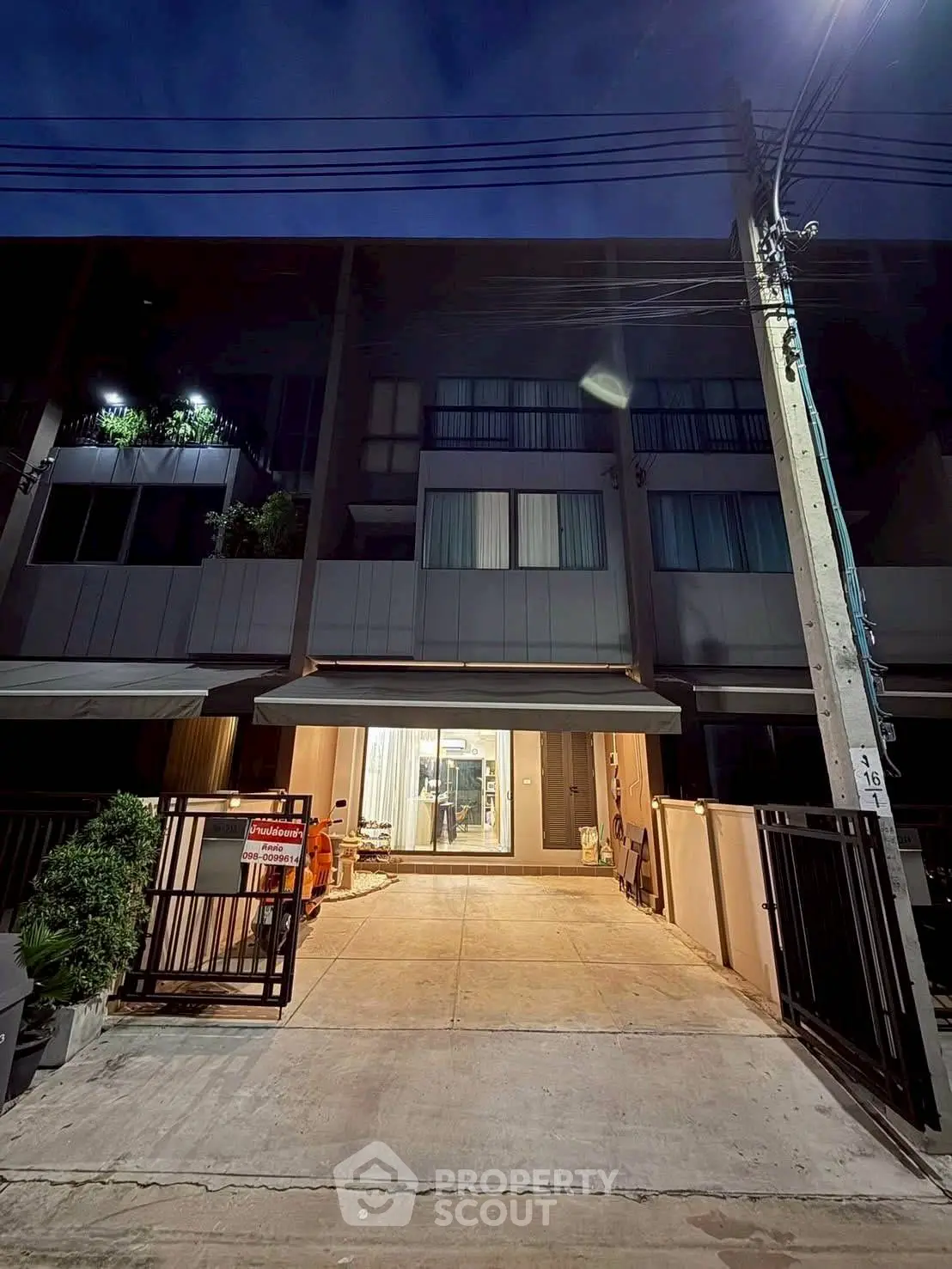 Modern townhouse exterior with illuminated entrance and driveway at night.