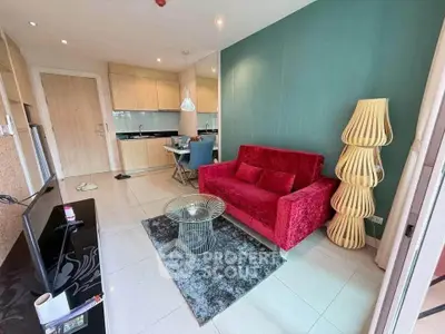 Modern living room with vibrant red sofa and stylish decor in open-plan apartment.
