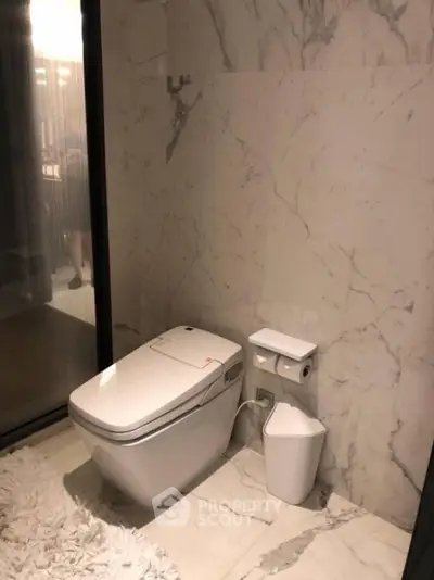 Luxurious marble bathroom with modern toilet and plush rug