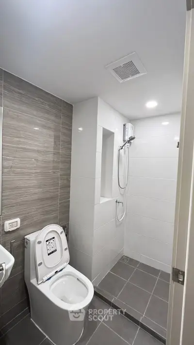 Modern bathroom with sleek design, featuring a shower and toilet in a compact space.