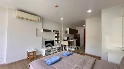 Modern studio apartment with open layout, featuring a cozy bed, compact kitchen, and stylish decor.