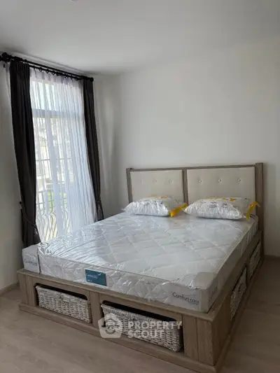 Modern bedroom with stylish bed and natural light from large window.