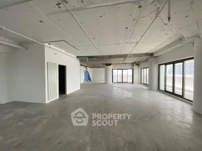 Spacious open-plan interior with large windows and concrete flooring, ideal for customization.